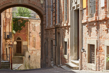 Street with red bricks buildings and ancient buildings in a sunny summer day in Mondovi, Italy