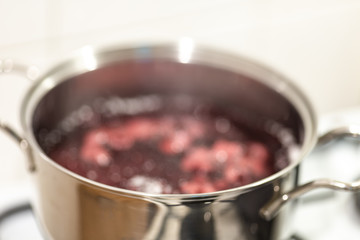 Blurred abstract background of blueberries boiling in a pan. Cooking blueberry jam.