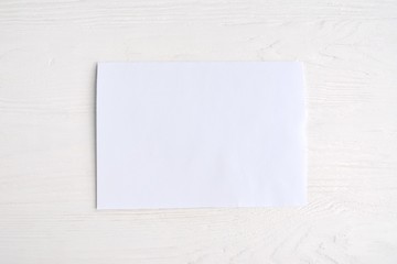 Blank sheet of white paper for design banner or card on textured neutral background, selective focus. Clear page with empty space for image or text on wooden white backdrop. Mockup concept 