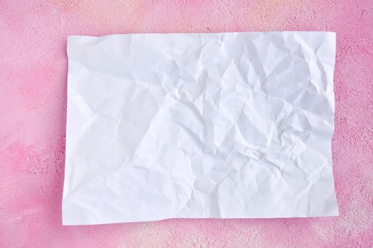 crumpled paper on pink plaster background for design banner or card, selective focus. Clear textured obsolete page with empty space for image or text on grunge pink backdrop. Mockup concept 