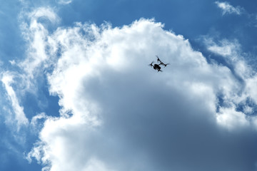 Naklejka na ściany i meble Flying quadrocopter on a background of clouds and blue sky