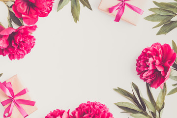 Flat lay composition with red peonies and gift box on a light background