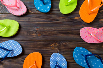 a lot of flip flop colored sandals, summer vacation on wooden background, copy space top view