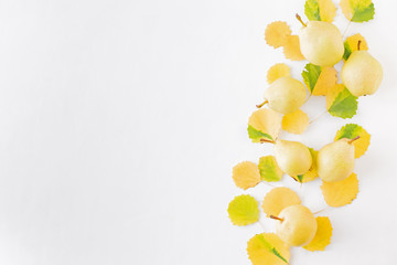 Flat lay pattern with colorful autumn leaves and yellow pears on a white background