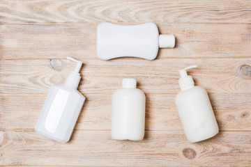 Set of White Cosmetic containers on wooden background, top view with copy space. Group of plastic bodycare bottle containers with empty space for you design