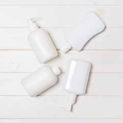 Set of White Cosmetic containers on wooden background, top view with copy space. Group of plastic bodycare bottle containers with empty space for you design