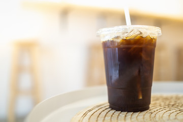 Close up of take away plastic cup of iced black coffee Americano on table in restaurant.