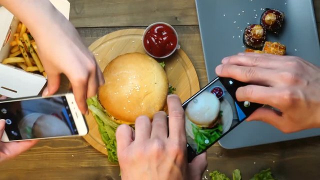 Couple using smartphones to take photos of food