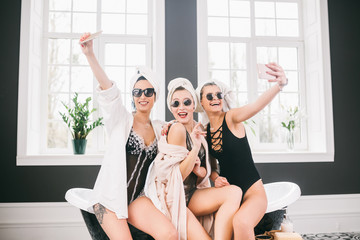 Picture showing group of happy friends in spa. girls with towels on heads having fun and taking...
