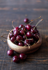 Dark red cherries in a bowl on wooden and gray  background 