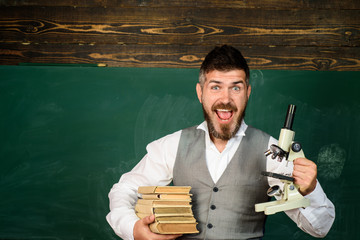 Teacher in classroom at elementary school. Confident male teacher in classroom. Teacher giving lesson to students. Education, high school and people concept - happy teacher over blackboard background.