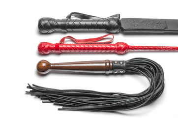 black and red three bdsm whips on a white background close up