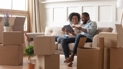 Happy african american couple use digital tablet on moving day