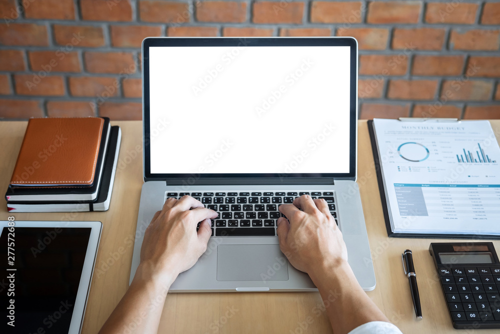 Wall mural image of young man working in front of the laptop looking at screen with a clean white screen and bl