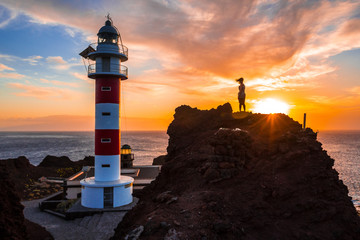 A young girl visiting the lighthouse at a sunset in Punta de Teno, Tenerife (Canary Islands)