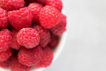 Fresh raspberry in white bowl on gray background. Top view.