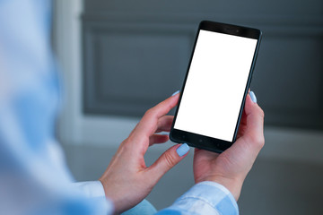 Mock up, copyspace, template and technology concept. Woman looking at black smartphone with white blank screen. Close up view of woman hands with smart phone mobile device - mockup image
