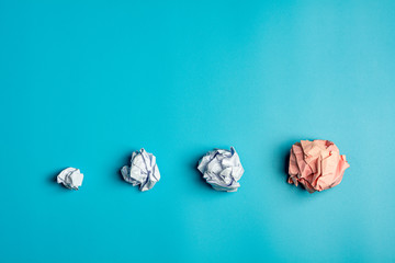 pile of a white crumpled paper balls on blue background.