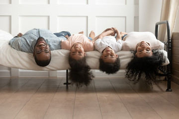 Happy african american family bonding lying upside down on bed