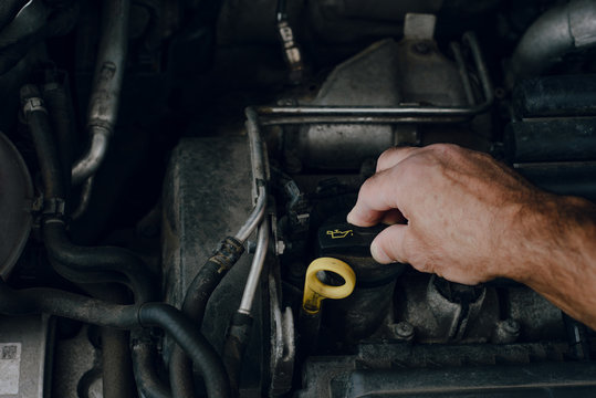 Checking liquids in the car. The man checks the level of fluids in the car with the car hood open. Concept of car breakdown, problems and attempts to locate a failure.
