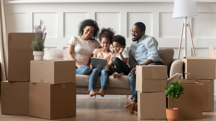 Happy african parents and children using tablet on moving day