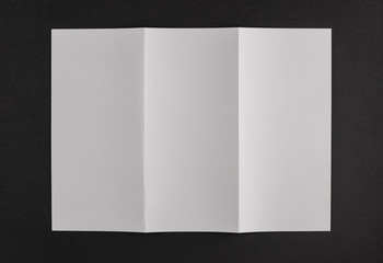 Blank open book with two folds on a black background. Blank white two folded booklet mock up. 