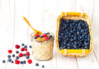 Muesli with blueberries in glass jar on white wooden background. The concept of a healthy breakfast. 