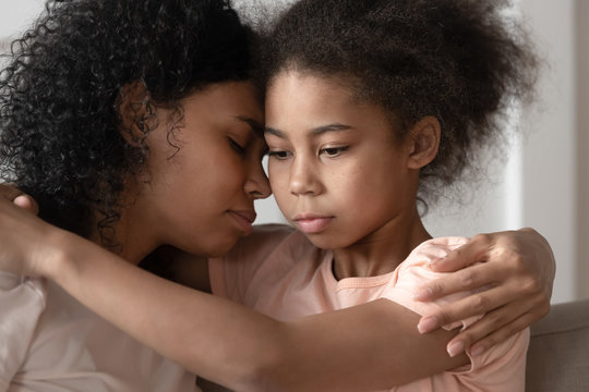 Thoughtful african american kid daughter embracing mom bonding cuddling