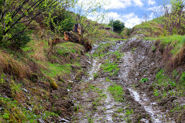 Dirty country road rises uphill on the slope.