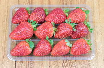 Box of fresh strawberry. Wooden background.