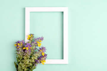 Yellow-violet flowers, photo frame on a green background. Top view, copy space. Flat lay.