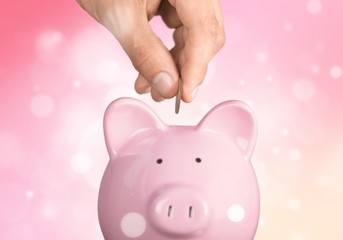 Hand putting coin to piggy bank and coins on white background