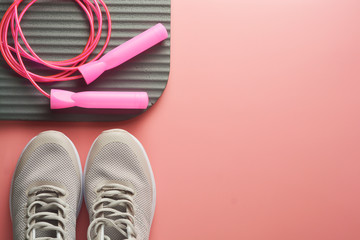 Workout concept, flat lay with copy space. Sport shoes, jumping rope, yoga clothes over pink background. Health, running workout, fitness and yoga concept. Feminine background.