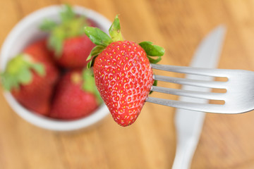 Fresh strawberry, fork and knife. Wooden background.
