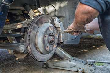 Closeup of a hand changing a brake pads on a car.