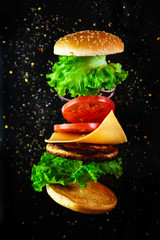 Flying ingredients for a homemade burger on a black background.