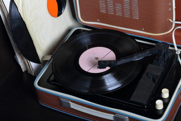 An old gramophone with a vinyl record mounted on it. Next to shabby paper envelopes are other...
