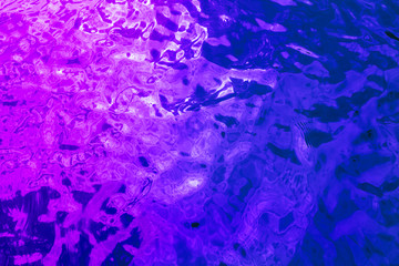 The surface of the water in the neon light. Trendy colors.
