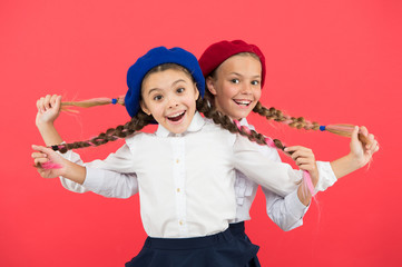 Friendship means support. Kids long braids hairstyle classmates friends. Girls best friends on red background. True friends always stand beside you. Cute playful sisters schoolgirls having fun