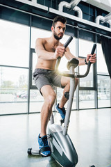 handsome sportsman training on elliptical machine at sports center