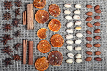 Dried orange slices, cinnamon and anise for decoration. Also pistachios and almonds are laid out in rows on coarse linen fabric.
