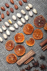 Fototapeta na wymiar Dried orange slices, cinnamon and anise for decoration. Also pistachios and almonds are laid out in rows on coarse linen fabric.
