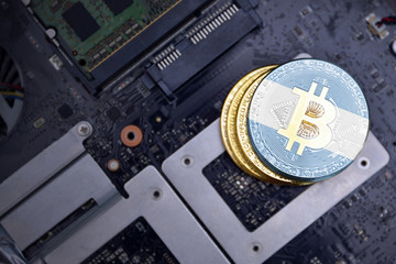 golden bitcoins with flag of argentina on a computer electronic circuit board. bitcoin mining...
