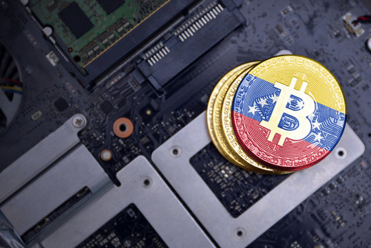 golden bitcoins with flag of venezuela on a computer electronic circuit board. bitcoin mining concept.