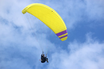 yellow paraglider in a blue sky