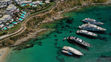 Aerial panoramic photo of famous turquoise clear sea celebrity sandy beach and bay of Psarou with yachts and sail boats in iconic island of Mykonos, Cyclades, Greece