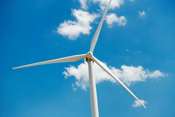 Electricity wind generator on bright cloudy sky background - wind energy and technology concept