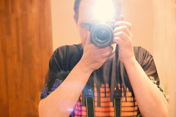 Photographer with camera make shot with flash in mirror