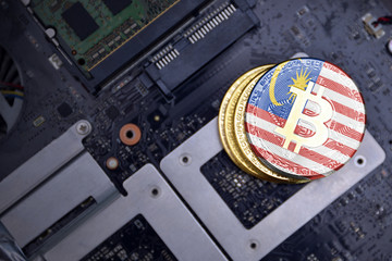 golden bitcoins with flag of malaysia on a computer electronic circuit board. bitcoin mining...