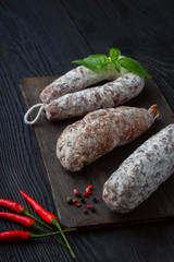 Aromatic regional pork sausage lying on a wooden board on black wooden  background